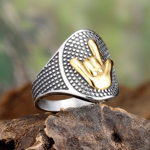Macro shot of punk signet ring with golden hand gesture relief on textured silver metal