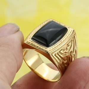 Detailed view of men's gold plated signet ring with rectangular black onyx stone inlay