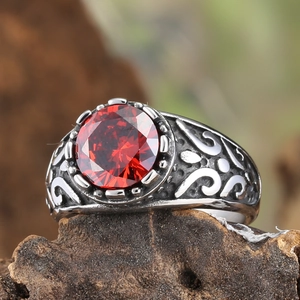 Macro detail of vintage steel ring featuring a large faceted red stone and carved relief