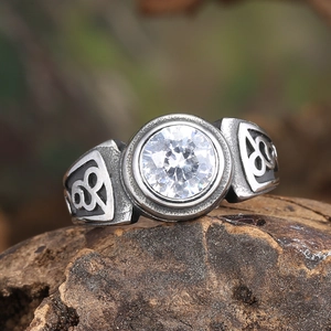Close-up of vintage steel ring with round zircon and Celtic knots on tree bark