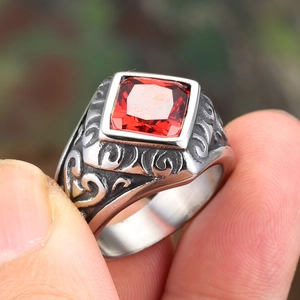 Macro shot of vintage steel ring featuring a square red zircon with floral engravings