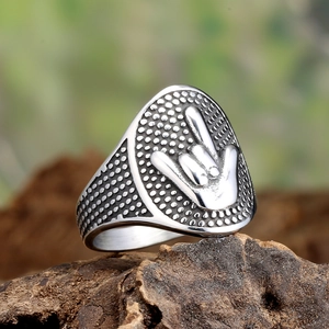 Macro detail of retro rock gesture relief on stainless steel shield ring outdoors