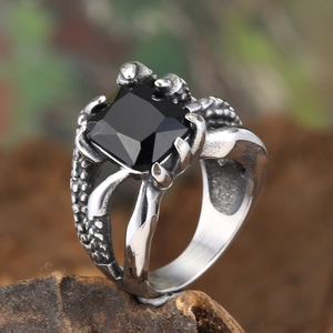 Macro detail of gothic claw ring holding a large square black stone on wooden base