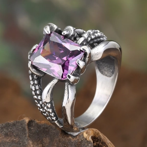 Gothic dragon claw ring with purple rectangular gemstone on rough stone background