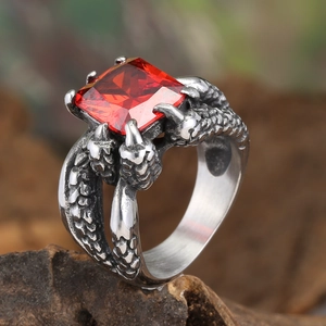 Close-up of gothic claw ring with large square red ruby stone on a natural rock