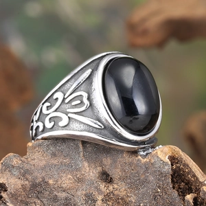 Macro view of vintage stainless steel men's ring with black stone and floral engraving