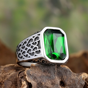 Macro shot of rectangular emerald-cut green stone ring with vintage engraved patterns