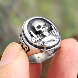 Macro shot of a silver punk skull ring featuring a bold middle finger hand gesture