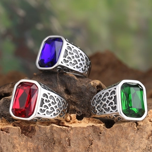 Vintage titanium steel rings with rectangular red, blue, and green gemstones on wood