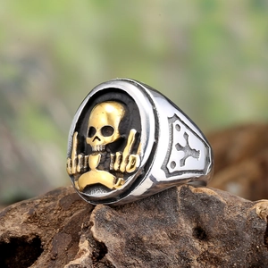 Punk style stainless steel skull ring with gold accent on rustic wood background