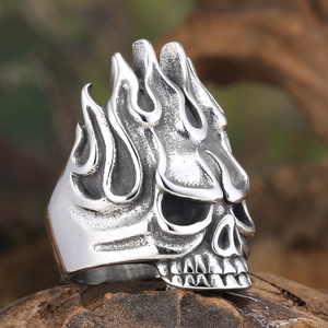 Detail view of vintage stainless steel skull ring with flame pattern on wood base