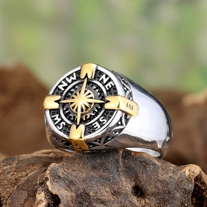 Macro view of two-tone compass ring with golden star and vintage engraved band