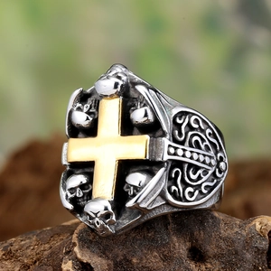 Retro punk skull ring with golden cross in stainless steel on dark wood texture