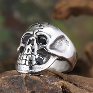 Macro shot of gothic titanium skull ring with black gemstones on textured wood