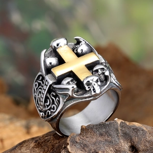 Macro detail of gothic stainless steel ring with gold cross and skull carvings