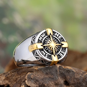 Vintage stainless steel compass ring with gold octagram star on aged wood background