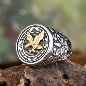 Vintage men's silver ring with gold eagle relief on wood, retro biker steel jewelry