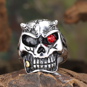 Macro shot of punk skull ring with red gemstone eye and vintage silver finish on wood
