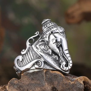 Vintage stainless steel Ganesha ring with intricate relief on a textured rock surface