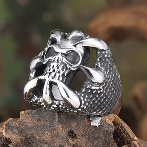 Macro shot of vintage silver skull ring with claw details on dark wood surface