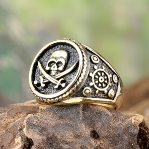 Macro detail of vintage gold pirate ring with skull, crossbones and ship wheel relief