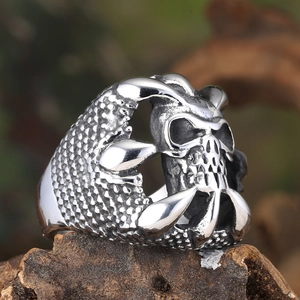 Close-up of vintage silver punk ring featuring skull and claw with scale texture on wood