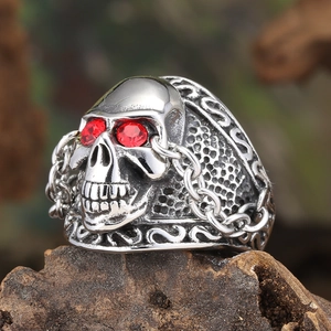 Macro view of vintage skull ring with red crystal eyes and ornate chain engravings