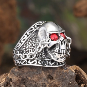 Close-up of gothic skull ring in vintage steel with red rhinestone eyes on rock