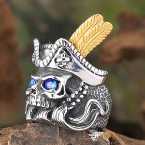 Macro view of pirate skull ring with gold feather and blue gem eyes on wooden base
