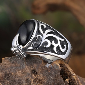 Detailed macro view of vintage steel eagle claw ring with black oval gemstone and floral motifs