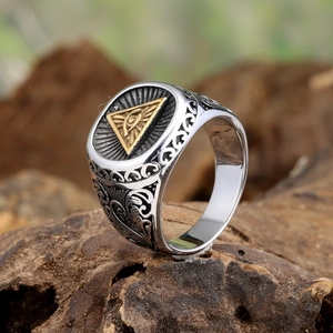 Vintage stainless steel ring featuring golden Eye of Providence on a wood background