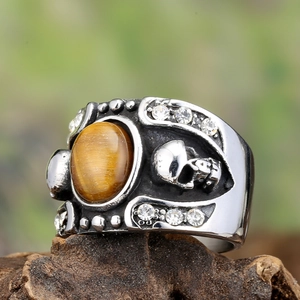 Retro stainless steel men's ring with tiger eye stone and skull relief on a wood base