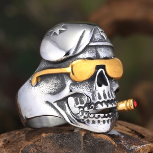 Détail macro d'une bague tête de mort rétro avec lunettes dorées et cigare rouge