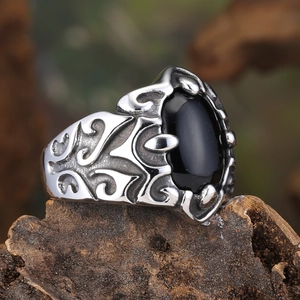 Close-up of vintage steel ring with black oval stone and intricate filigree details
