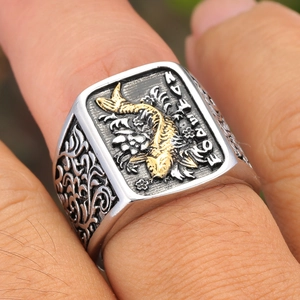 Détail macro d'une bague pour homme en acier avec relief de carpe koi dorée et volutes