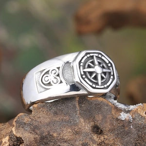 Gros plan sur bague boussole vintage en acier avec nœuds celtiques sur fond de bois