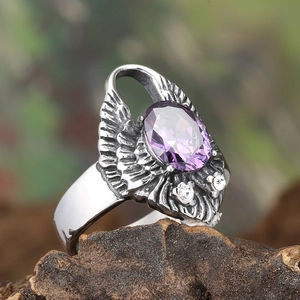 Détail macro d'une bague ailes rétro avec pierre ovale violette sur bois rustique