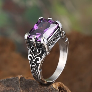 Macro shot of vintage silver ring featuring a large rectangular purple gem and carvings