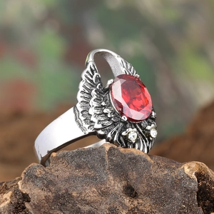 Vue détaillée d'une bague ailes d'ange gothique avec gemme rouge ovale sur bois