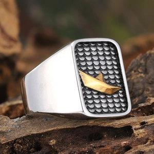 Macro detail of men's titanium ring featuring golden paper boat on black fish scale texture