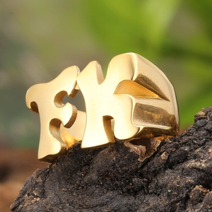 Vue macro d'une bague FK dorée épaisse posée sur un fond d'écorce naturelle