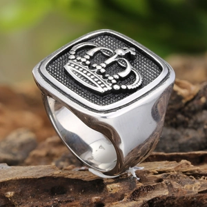 Herrenring aus Edelstahl in Silber mit Kronenrelief auf Holzgrund im Punk-Stil