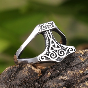 Detailed view of Viking Mjölnir ring with Celtic knot patterns on a rustic bark surface