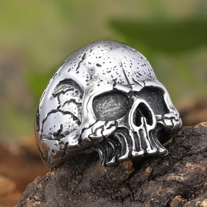 Vintage Gothic skull ring in distressed stainless steel on rustic bark with green background