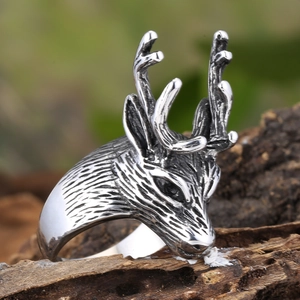Detail of vintage silver buck head ring with textured antlers on rustic wood bark