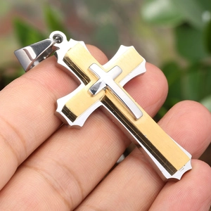 Detail view of a triple-layered stainless steel cross pendant with gold and silver finishes