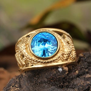 Vintage gold ring with large blue gemstone and embossed dragon scales on a wooden base