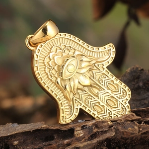 Macro shot of golden Hamsa Hand pendant with Evil Eye detail on dark wood texture