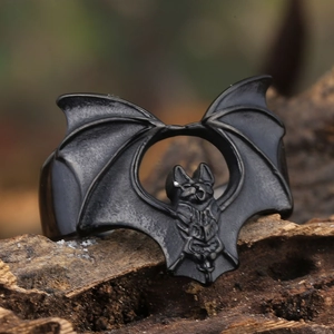 Macro detail of gothic black bat ring showing textured wings on dark wood background