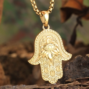 Gold Hamsa Hand pendant with Evil Eye and Lotus on a wooden background